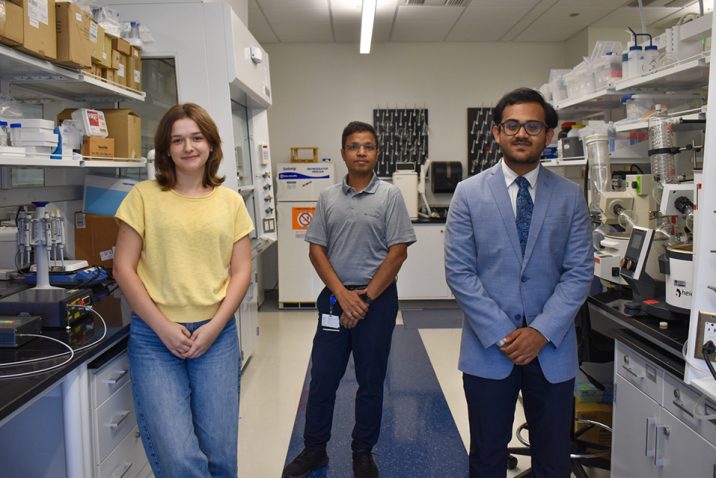 woman and two men standing together in a laboratory