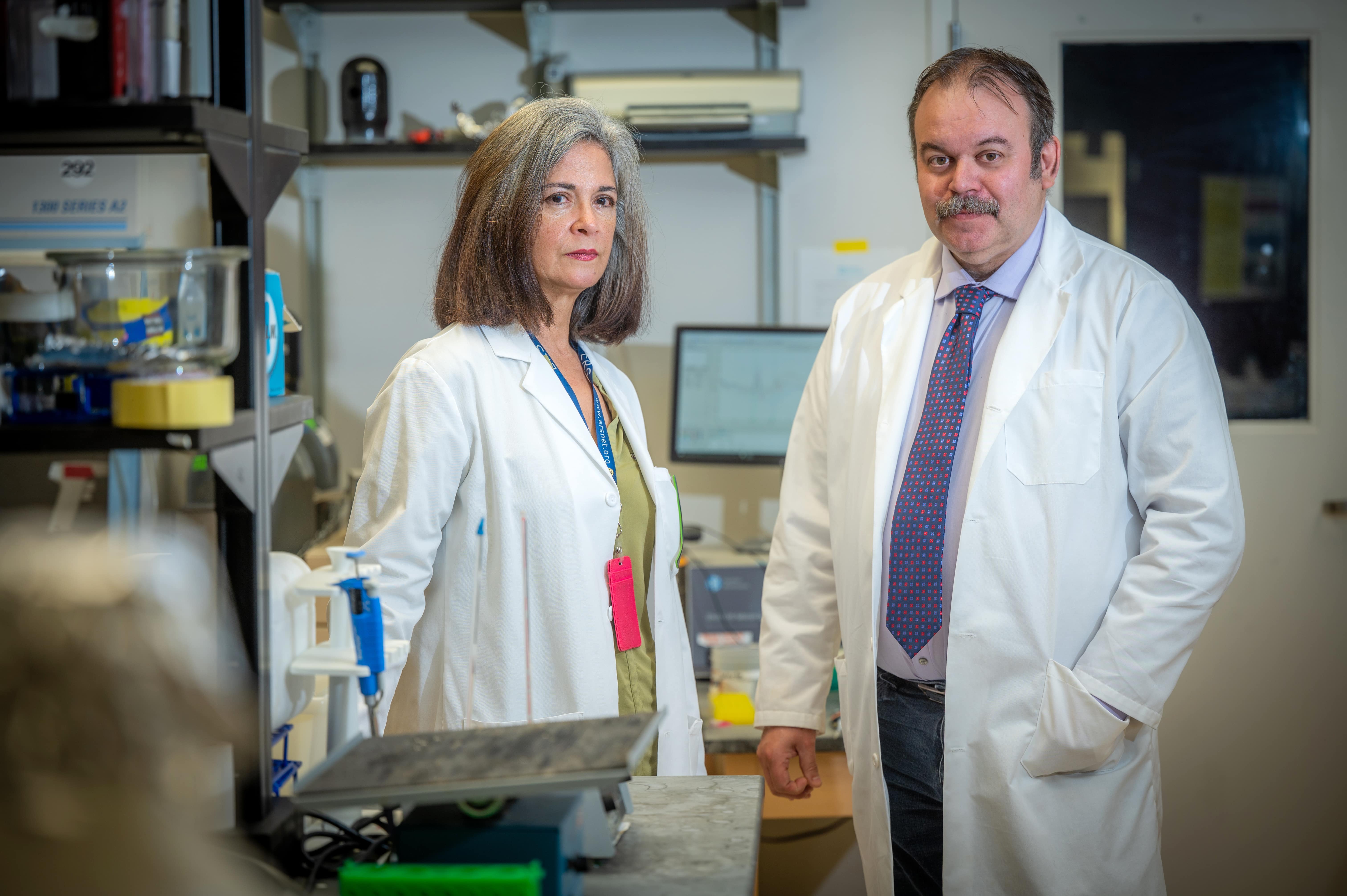 A man and woman in lab coats stand together in a scientific lab.