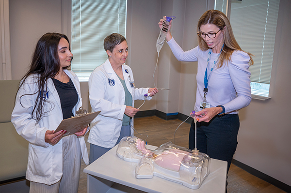 Translucent trainer manikin laying on an examination bed.