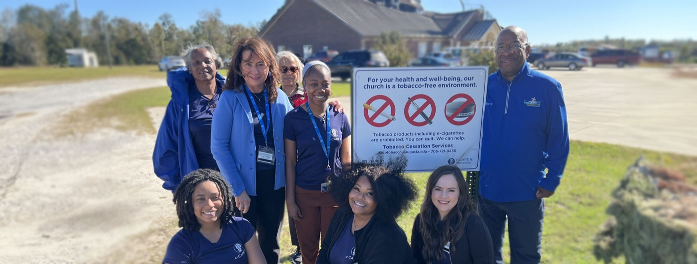 Ccare faculty & staff pose in front of sign