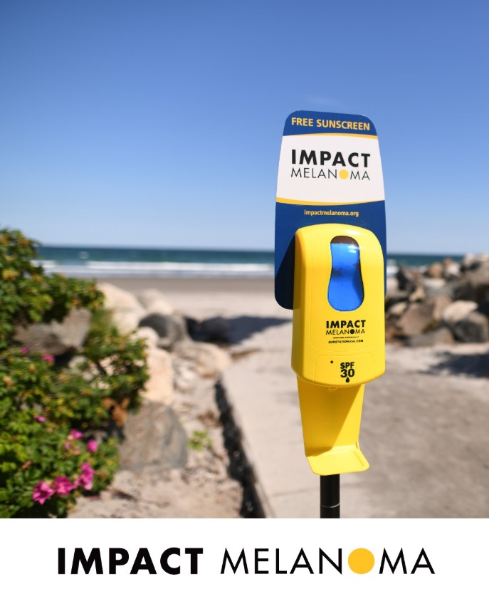 A Sunscreen dispenser outside from Impact Melanoma with the words "Impact Melanoma" underneath