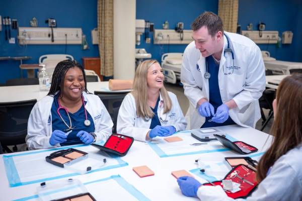 Students wearing white coats sitting at a table