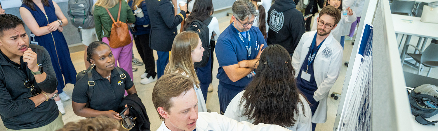 Attendees of the research symposium examine posters by participants describing their research projects and their results