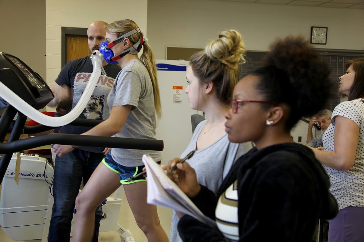A kinesiology professor guides a college student on using technology to measure blood oxygenation.
