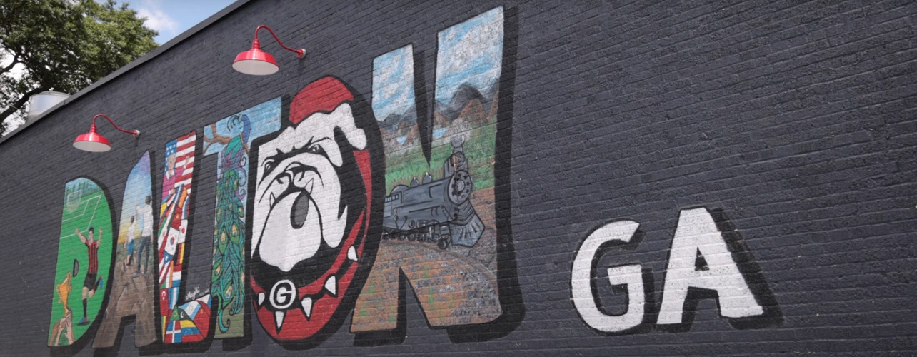Dalton, Georgia painted on a wall with each letter made from a different painting that represents Dalton, Ga