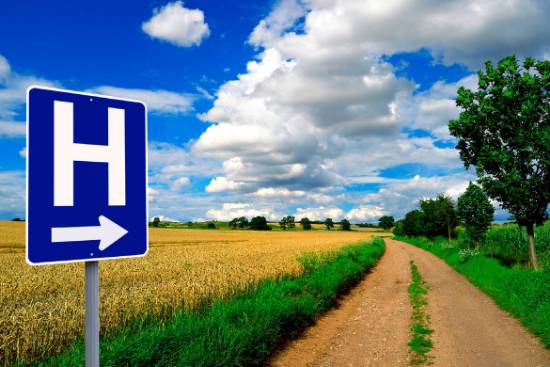 a hospital sign pointing down a dirt road