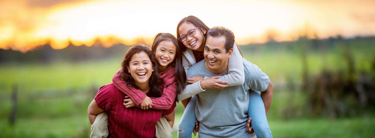 Family poses for camera with children piggyback on their parents