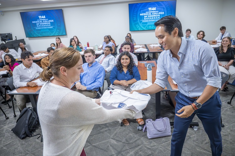 Dr. Gray hands students his white coat