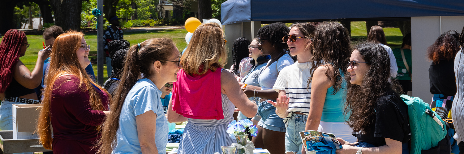 A professor and student talking at a table outside at an event
