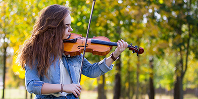 Young woman playing a violin outdoors