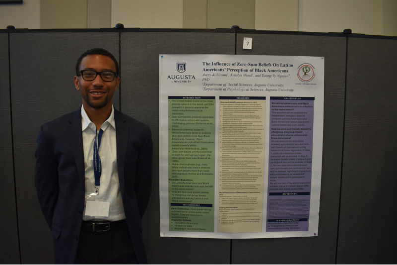 man smiling next to poster