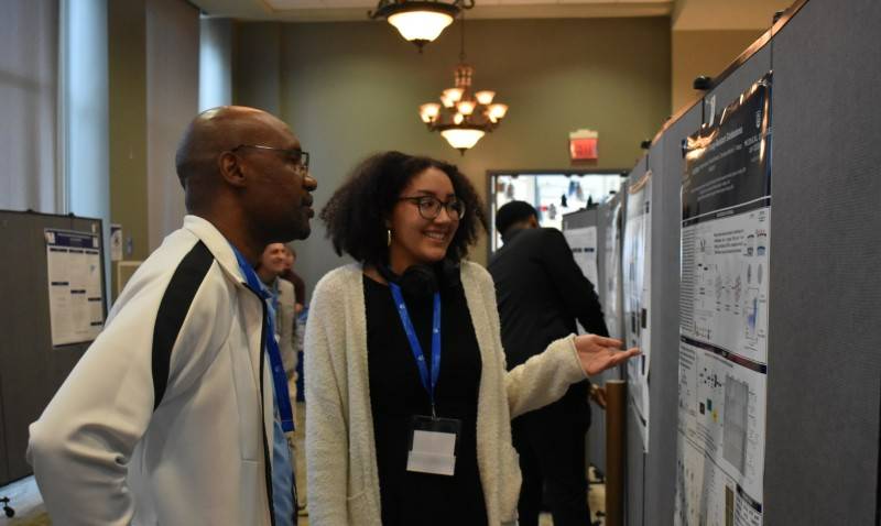 student presenting poster to another person