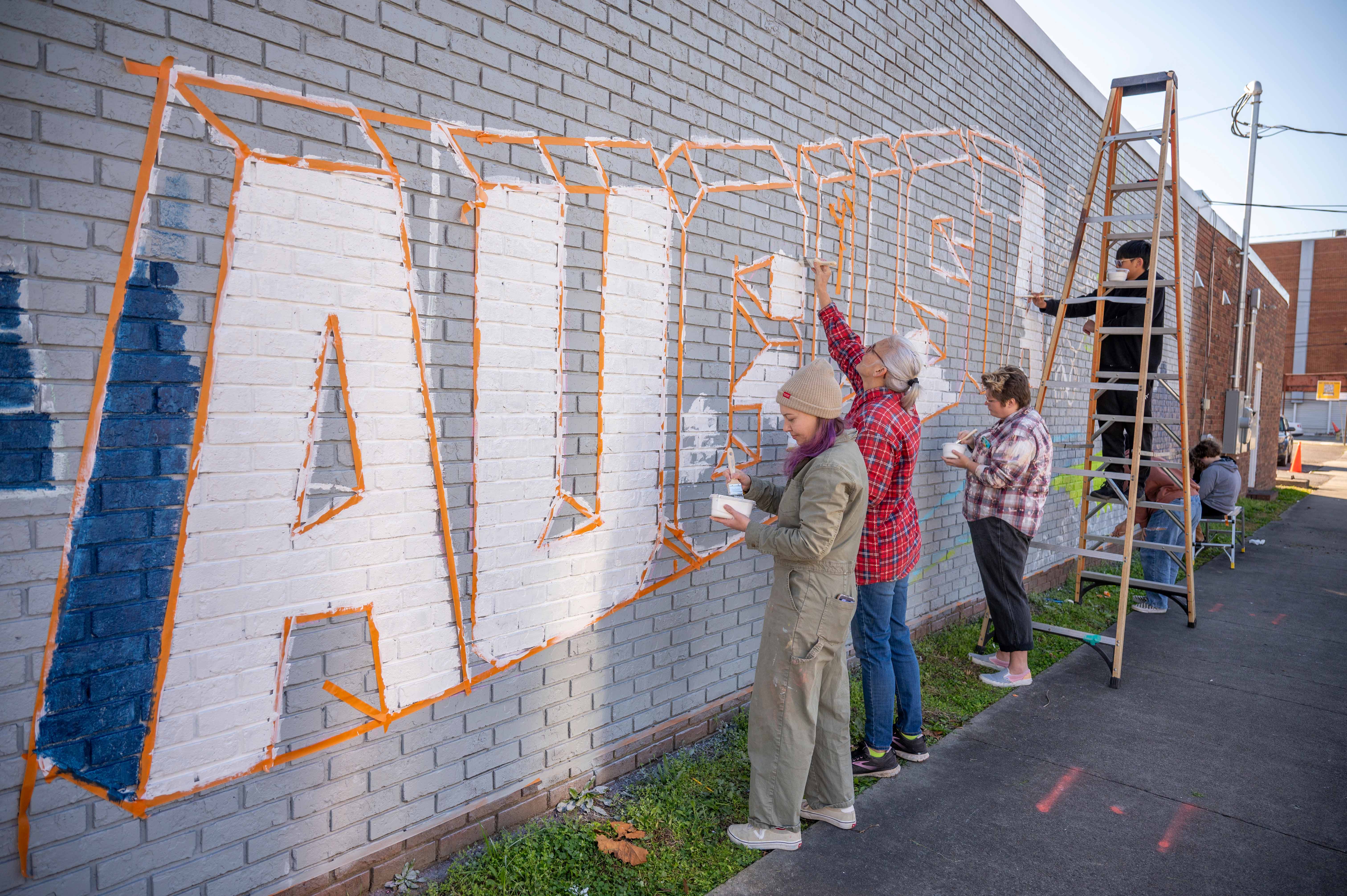 students and volunteers painting mural 