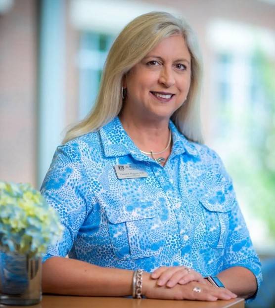 woman wearing a blue top leans against a countertop