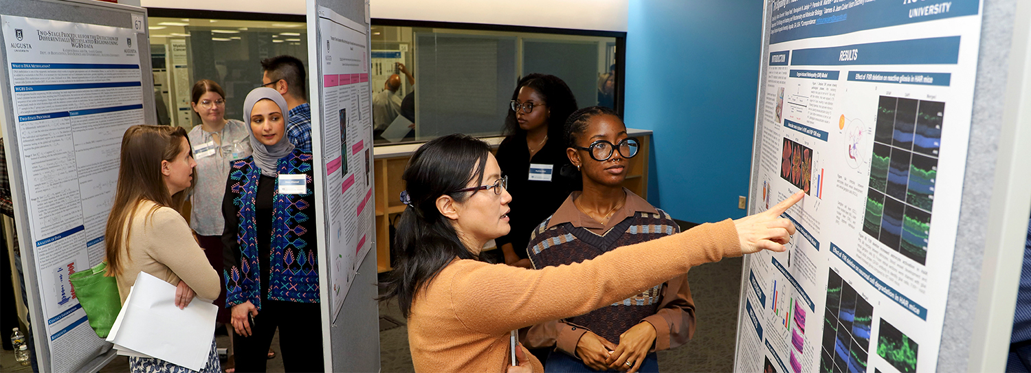 students and reviewers looking at research posters