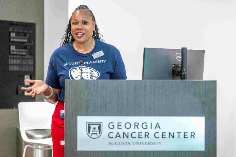 A Graduate Ambassador speaks at a podium in the Georgia Cancer Center at Augusta University