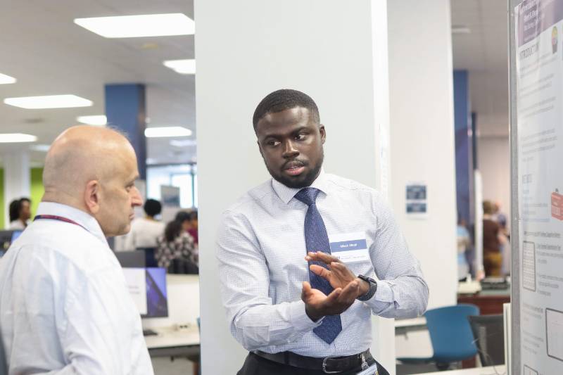 A student presents a poster to a faculty member
