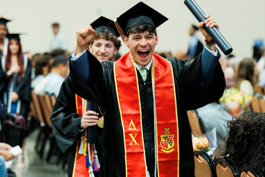 Alex Gonzalo holding diploma Excited graduate holding diploma tube