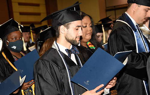 Graduates look at program during Commencement
