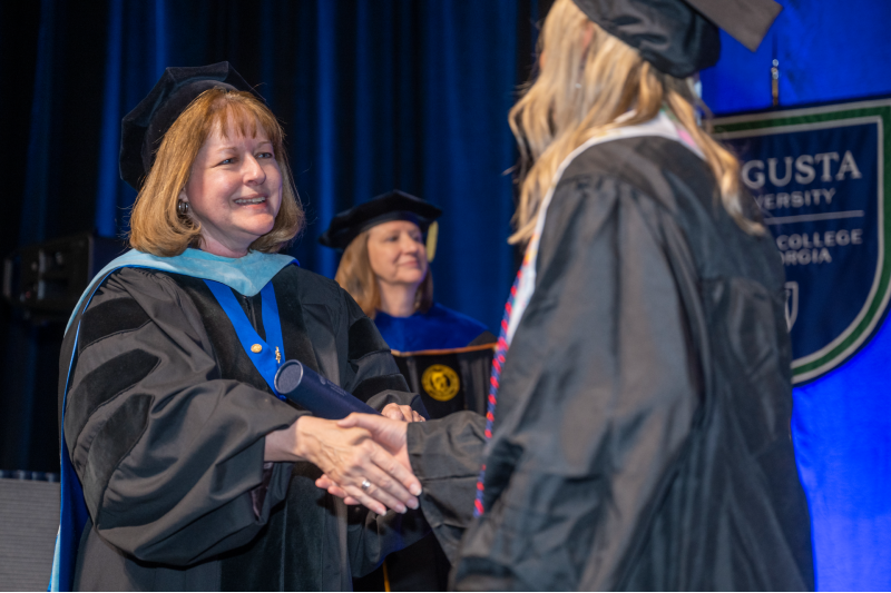 woman smiling and shaking hands with a student