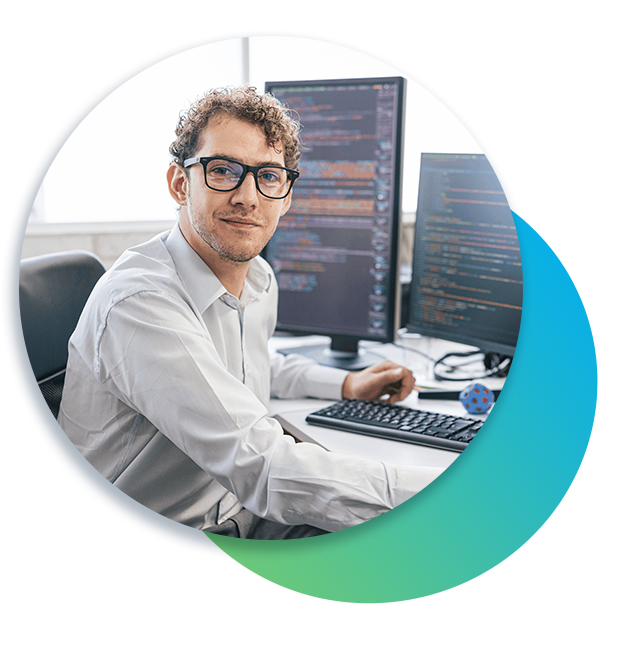 Online graduate student looks at camera with data analysis on monitors in the background