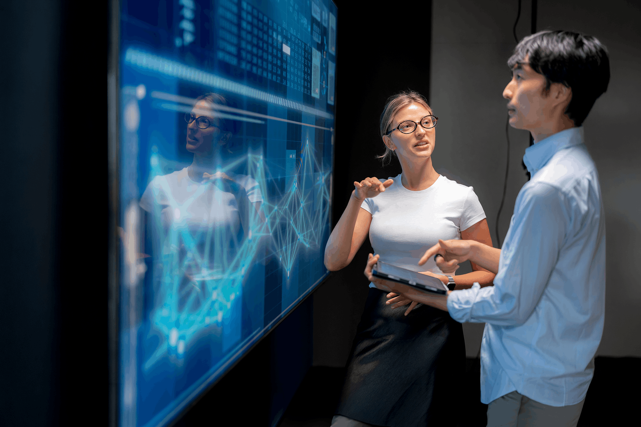 Data scientists discuss findings that are displayed on a large screen