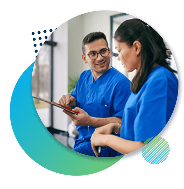 Two nurses review class material together in clinic lobby.