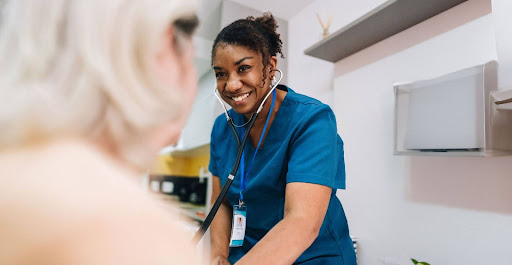 A smiling nurse listens to a patient in clinical setting