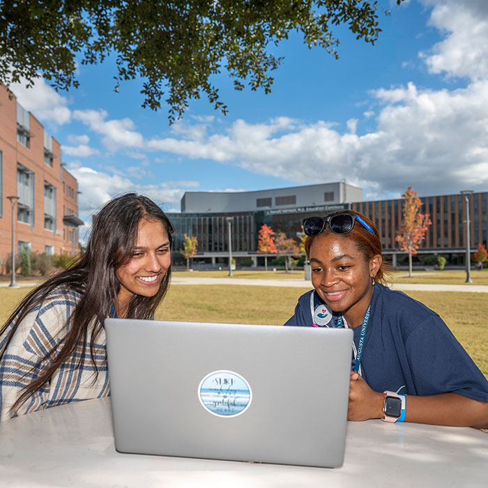 Two Female Students sitting with a laptop between them