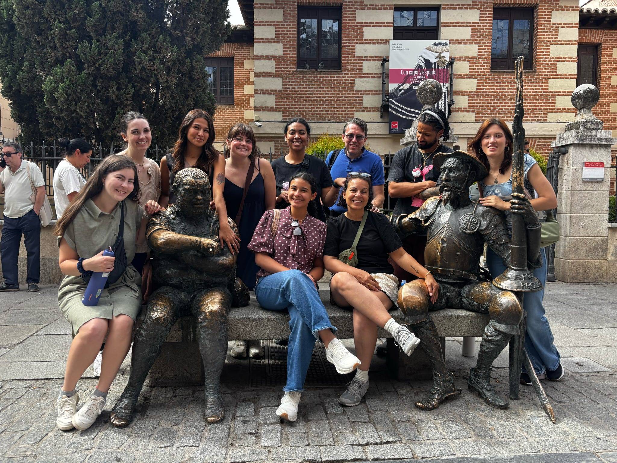 students posing in front of statue