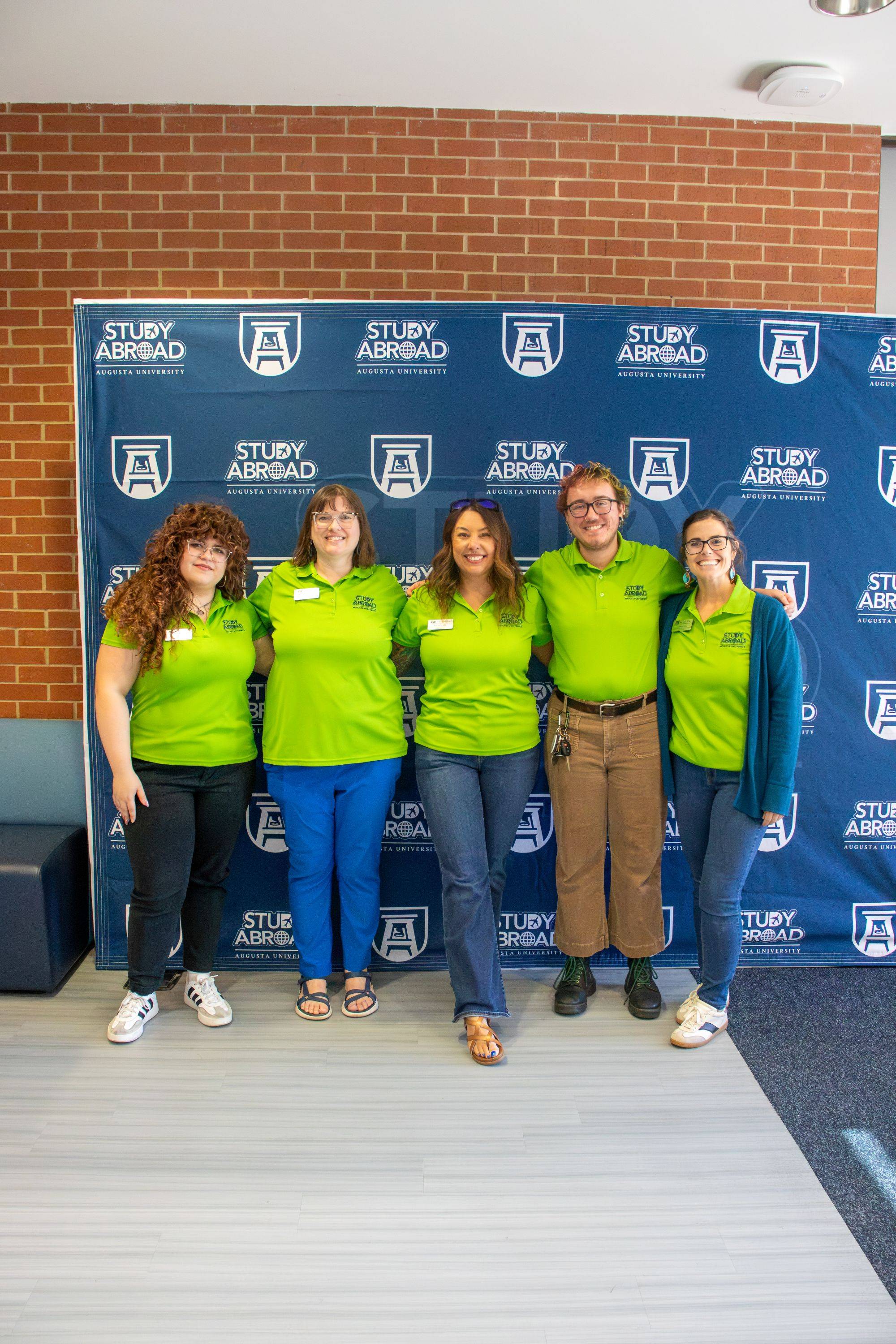 group in green pose for photo with backdrop