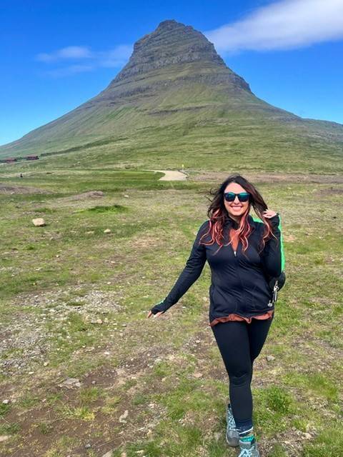 woman stands in front of green mountain