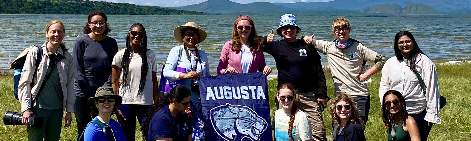 Study Abroad students from Augusta University pose for a group photo in front of a lake in Kenya with mountains in the background