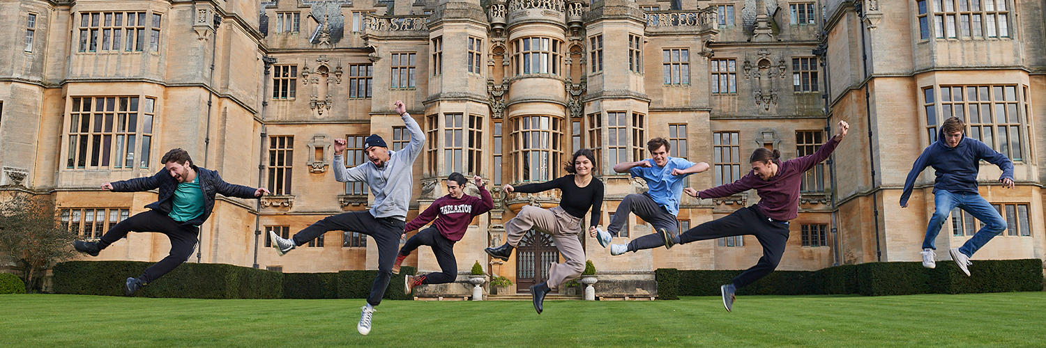 Study abroad students jump in the air in front of Harlaxton College