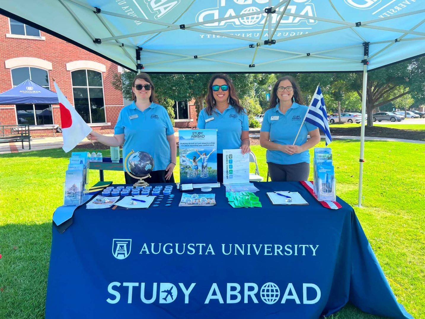 three women standing behind promotional table