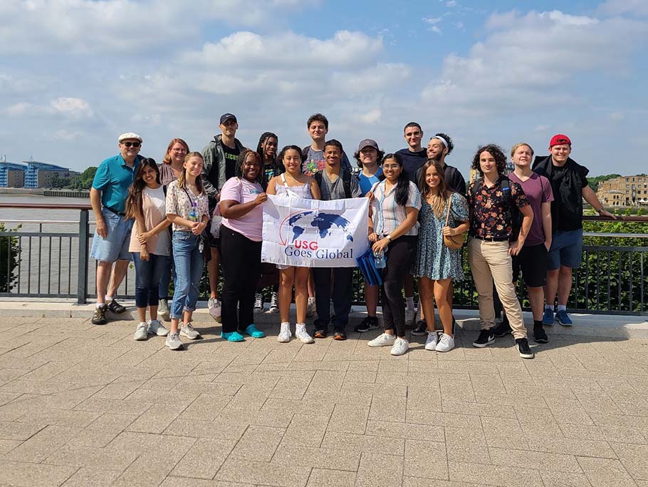 group of students on bridge holding a flag