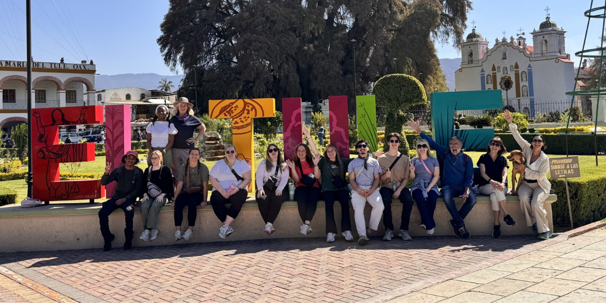 Students posing in front of a colorful sign