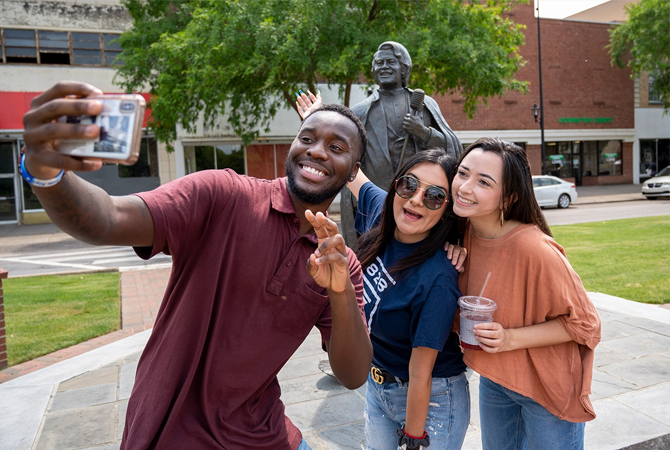 Students posing for a selfie in front of the statue of James Brown in Downtown Augusta